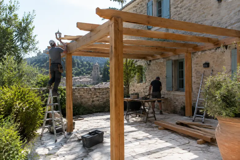 Installation d'une pergola en bois sur une terrasse de plain-pied dans un jardin de village
