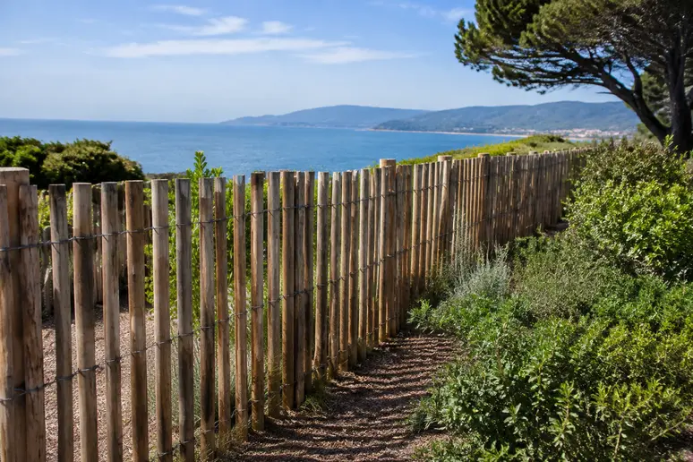 Clôture en bois ajourée protégeant un jardin littoral des vents marins